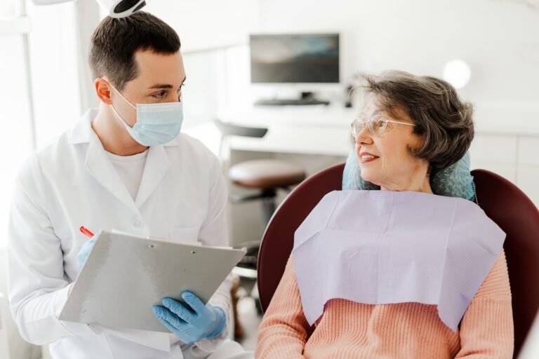 Young dentist doctor talking to retired patient, writing complaints, working in modern dentistry